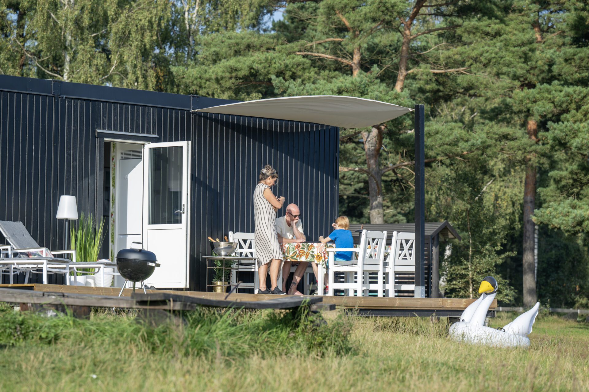David Elg Moob boibod 13 Svart bostadsmodul med familj på altanen som äter grillad mat