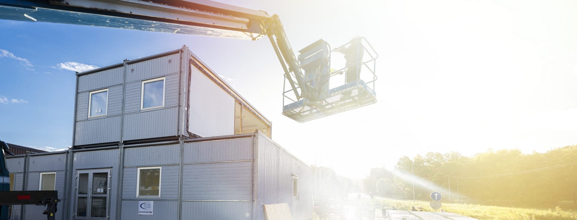 Montering av ett antal gråa bodar. En Skylift används för att komma åt våning två